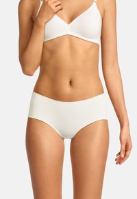 Weißer nahtloser BH mit verstellbaren Trägern, einem weichen Stoff und einer glatten Textur, kombiniert mit passenden weißen High-Waist-Slips.