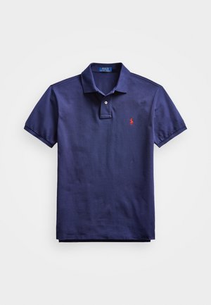 Mørkeblå polo-skjorte med krage, to-knaps placket, korte ermer og en liten rød logo på brystet. Stoffet er i bomull med en glatt tekstur.