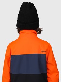 Persona che indossa un berretto nero e una giacca color block arancione, blu navy e nera con un piccolo logo sul lato destro della parte superiore della schiena.