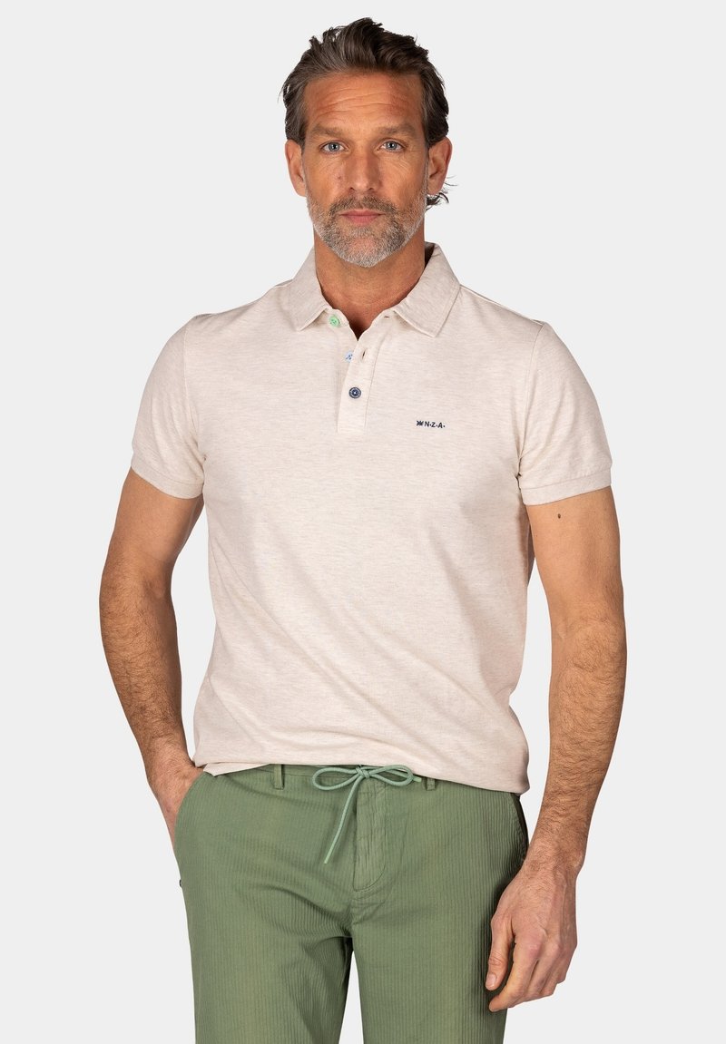 Heren polo met korte mouwen in lichtbeige stof; heeft een kraag met twee knopen en een klein logo. Gecombineerd met groene gestreepte broek.