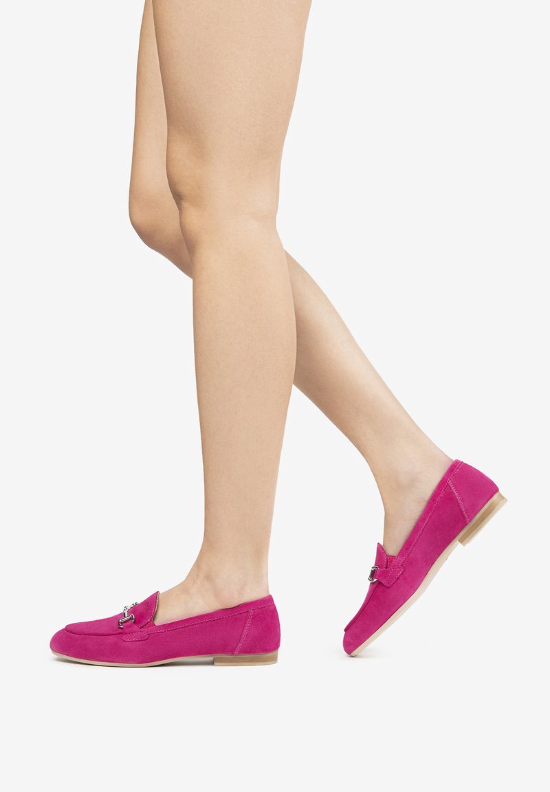 Lyse pink flade loafers i ruskind med rund tå, en lille spænde detalje og en lav beige sål, præsenteret mod en hvid baggrund.