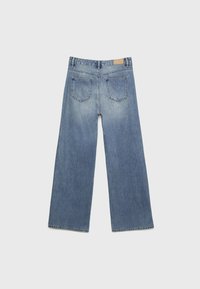 Ljusblå vida jeans med två bakfickor och en läderpatch på midjan, visade platt mot en neutral bakgrund.