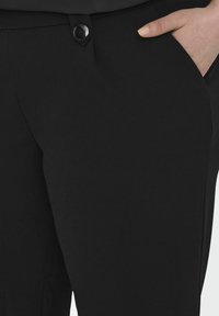 Černé kalhoty z hladkého materiálu, s knoflíkovým zapínáním a bočními kapsami. Elegatní design se štíhlým střihem.