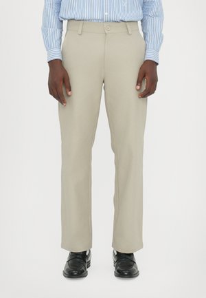 Beige tailored trousers made of a smooth fabric, featuring a button closure, straight-leg design, and side pockets. Worn with black shoes.