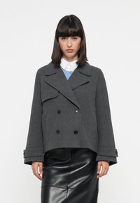 Grå ullblandings peacoat med dobbeltrykknapfront, store svarte knapper, bred krage og korte ermer, parret med et skjørt i svart lær.