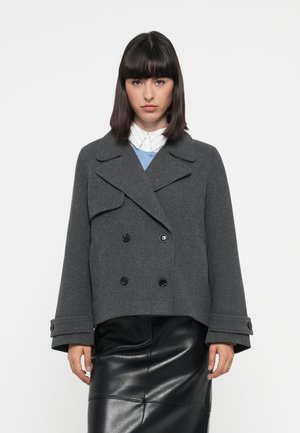 Grå ullblandings peacoat med dobbeltrykknapfront, store svarte knapper, bred krage og korte ermer, parret med et skjørt i svart lær.