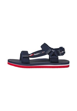 Navy blue sandal with adjustable fabric straps, a textured sole, and a red and white accent on the bottom edge. Logo on the strap.