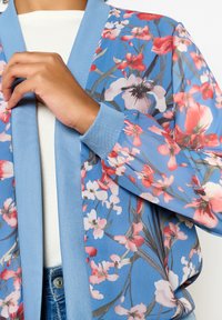 Viegls, caurspīdīgs zils kimono ar ziedu rakstu. Iespējas ir elastīgas aproces un atvērtā priekšpuse. Ziedu raksti ietver rozā un baltas puķes.