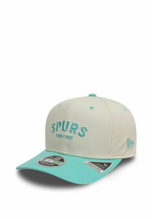 Cappello beige chiaro con visiera turchese e testo ricamato "SPURS". Presenta una chiusura snapback regolabile e dettagli in tessuto texturizzato.