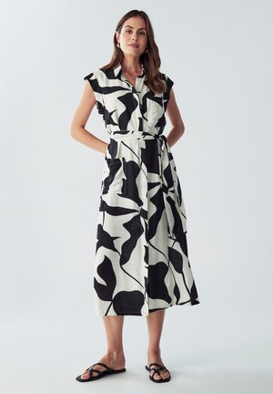 Black and white patterned dress with a shirt collar, short sleeves, waist tie, and pockets, made from a lightweight fabric, mid-length design.