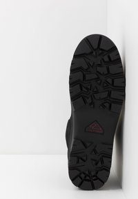Černá gumová podrážka s hlubokými vzory a trojúhelníkovým logem. Boční pohled ukazuje texturovaný svrchní materiál s vyztuženými sekcemi.