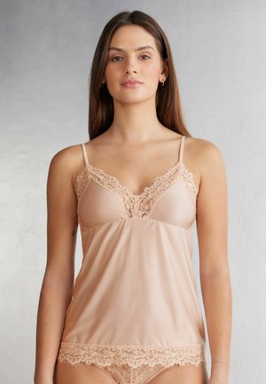 Nude camisole met kantafwerking en verstelbare bandjes. Zachte, gladde stof met ingewikkelde kantdetails bij de halslijn en zoom. Eenvoudig, elegant ontwerp.