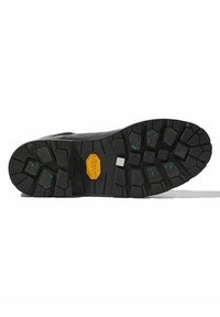 Suela Vibram negra con un patrón de relieve robusto. Presenta el logo de Vibram en amarillo, con motitas azules incrustadas en la goma para mejorar la tracción.