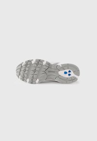 Gray sneaker outsole with a textured rubber design, featuring white accents and three blue circular details in the heel area.