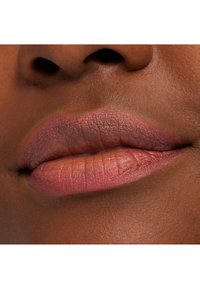 Matte leppestift på leppene, med en rosa-brun nyanse og en subtil glød. Glatt tekstur med synlige leppeliner og konturer.
