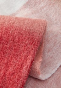 Soft felt fabric in gradient shades of coral and light pink, showcasing a fluffy texture and a smooth surface, folded and layered.