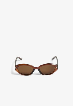 Lunettes de soleil ovales marron avec une monture translucide en écaille et des branches noires, placées sur un fond blanc.