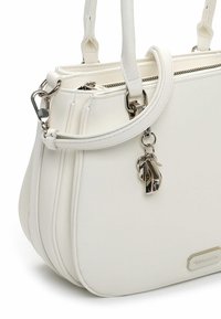 Borsa bianca in ecopelle con due manici, chiusura con cerniera e un portachiavi decorativo. Presenta cuciture sottili e una targhetta con logo in metallo.