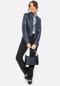 Giubbotto in pelle blu navy corto con tasche con cerniera, abbinato a pantaloni neri, una sciarpa con motivo e una borsa blu navy testurizzata con tracolla a catena.
