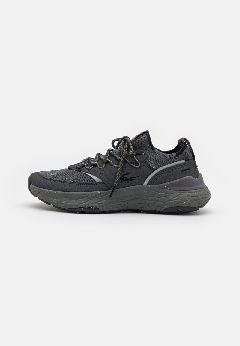 Baskets de sport gris foncé avec semelle épaisse texturée, tige tricotée, fermeture à lacets et logo de la marque sur le côté, vues de l’extérieur.