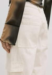 Witte cargo broek met een relaxte pasvorm, twee zijzakken en een gladde textuur. De stof lijkt duurzaam met zichtbare stiksels.