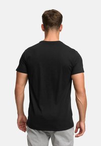 Black short-sleeve t-shirt displayed from the back, featuring a crew neck and a smooth cotton texture. Casual fit, minimalistic design.