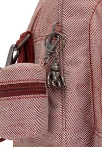 Rød og hvid sildemønstrede taske med en lille lynlås pouch og en metalastronaut nøglekæde vedhæftet.