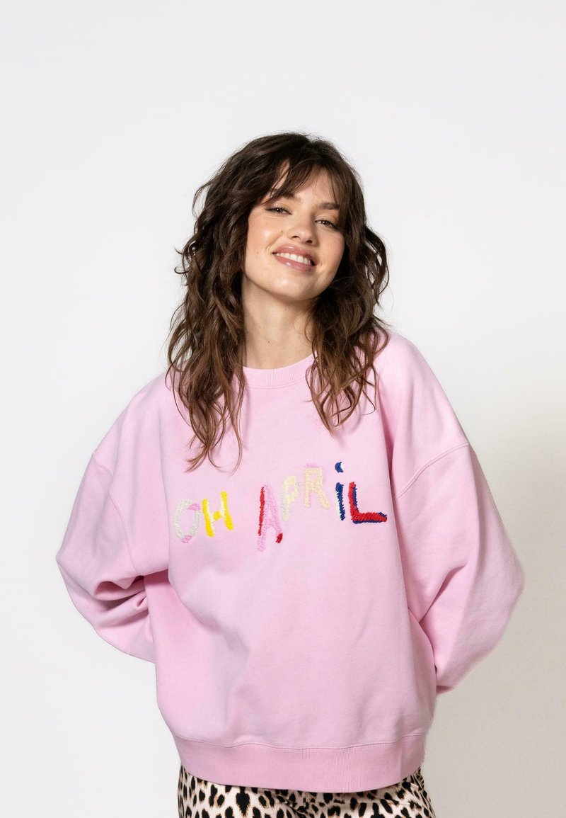 Hellblau übergroßes Sweatshirt mit buntem gesticktem Text "OH APRIL" auf der Vorderseite. Weicher Stoff, runder Halsausschnitt und gerippte Bündchen.