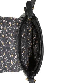 Svart läder crossbody-väska öppen för att visa blommönstrad foder och zipp-ficka inuti.
