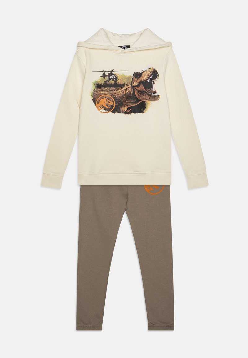 Creme hoodie med dinosaur grafik og helikopterprint; parret med brune leggings med et orange logo. Blødt bomuldsblandingsmateriale.
