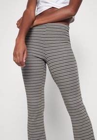 Legginsy w czarno-kremowe paski o dopasowanym kroju, wykonane z elastycznego materiału i z wysokim stanem, podkreślające gładką strukturę.