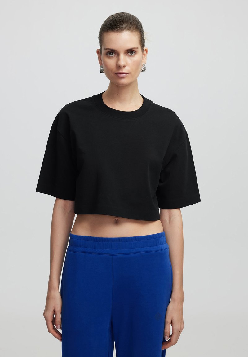 Zwart crop t-shirt met korte mouwen, ronde hals en een relaxte pasvorm, gecombineerd met blauwe sweatpants met een elastische tailleband.