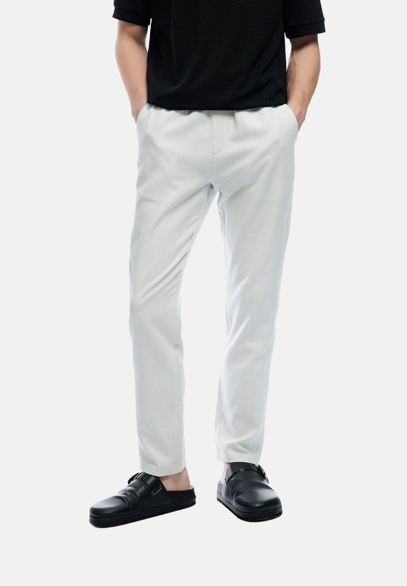 Lichtgrijze broek met een taps toelopend ontwerp en gestructureerde stof. Gepaard met zwarte instappers met gesps Accent.