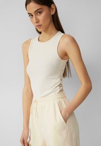 Beige geribbelde tanktop met een getailleerd ontwerp en ronde halslijn, gecombineerd met lichtkleurige sweatpants met zijzakken en een trekkoord.