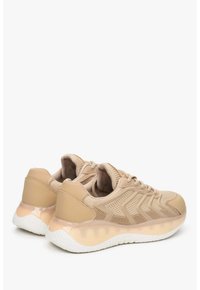 Beżowe buty sportowe z siateczkową cholewką, teksturowanym wzorem i błyszczącą podeszwą środkową z białą gumową podeszwą. Sznurowadła zapewniają pewne dopasowanie.