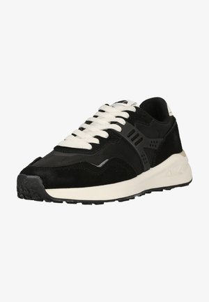 Black low-top sneaker with white thick sole, white laces, mesh and suede upper, and textured black rubber outsole.