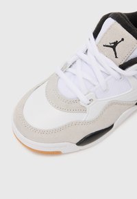 Zapatilla blanca y gris con acentos de ante, parte superior de malla texturizada y detalles en negro. Presenta una suela de goma con un patrón de banda de rodadura circular.