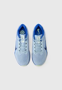 Zapatillas deportivas de color azul claro con parte superior de malla transpirable, acentos azules, cordones planos, forma curvada y suela texturizada. Presentan el logotipo de Nike.