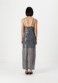 Rochie transparentă gri cu imprimeu de leopard negru, bretele subțiri, și un design lung și fluid, având un spate adânc și o textură ușoară.