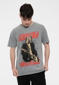 Gray cotton t-shirt featuring a large graphic print of a musician holding a guitar, with red text reading "KURT" and "COBAIN."