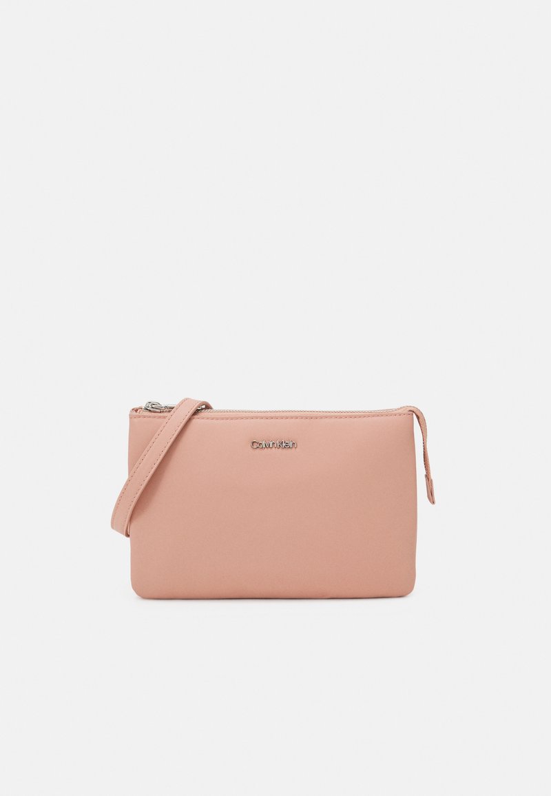 Pochette rosa con cerniera realizzata in materiale liscio, dotata di una tracolla staccabile e di un logo argentato sul davanti. Forma rettangolare.