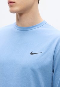 Ανοιχτό μπλε κοντομάνικο μπλουζάκι με στρογγυλή λαιμόκοψη από απαλό ύφασμα, με μικρό μαύρο λογότυπο Nike στην αριστερή πλευρά του στήθους. Ομαλή υφή, άνετη εφαρμογή.