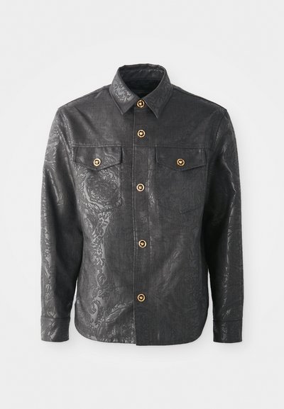 Black button-up shirt made of textured fabric, featuring a subtle floral pattern, gold-tone buttons, and two chest pockets.
