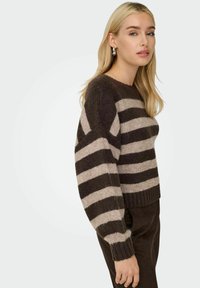 Pull rayé en marron foncé et beige, fabriqué à partir d'un matériau tricoté doux. Il présente un col rond et des poignets côtelés, avec une coupe décontractée.