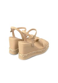 Sandali con zeppa beige in materiale sintetico liscio, con cinturini larghi e suola in juta intrecciata. Presentano una fibbia rotonda e un design con piattaforma.