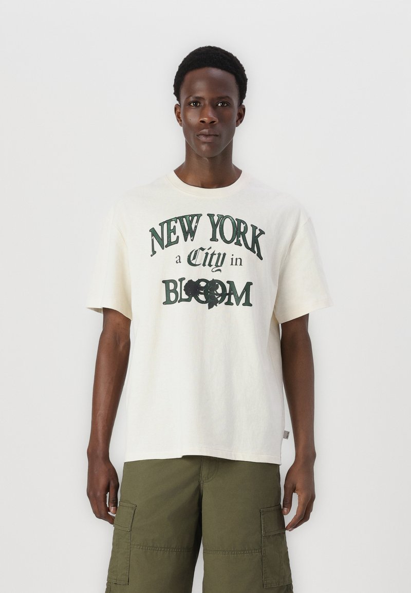 Cremefarvet bomulds T-shirt med teksten "NEW YORK a City in BLOOM" i grøn, med et afslappet fit og korte ærmer.