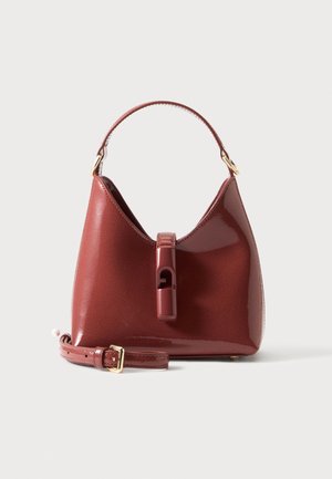 Sac à main rouge foncé brillant avec une poignée et une bandoulière détachable placé devant sur un fond clair uni.