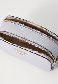 Light gray textured fabric purse with two zippered compartments and gold-tone hardware. Features a brand plaque on the front.