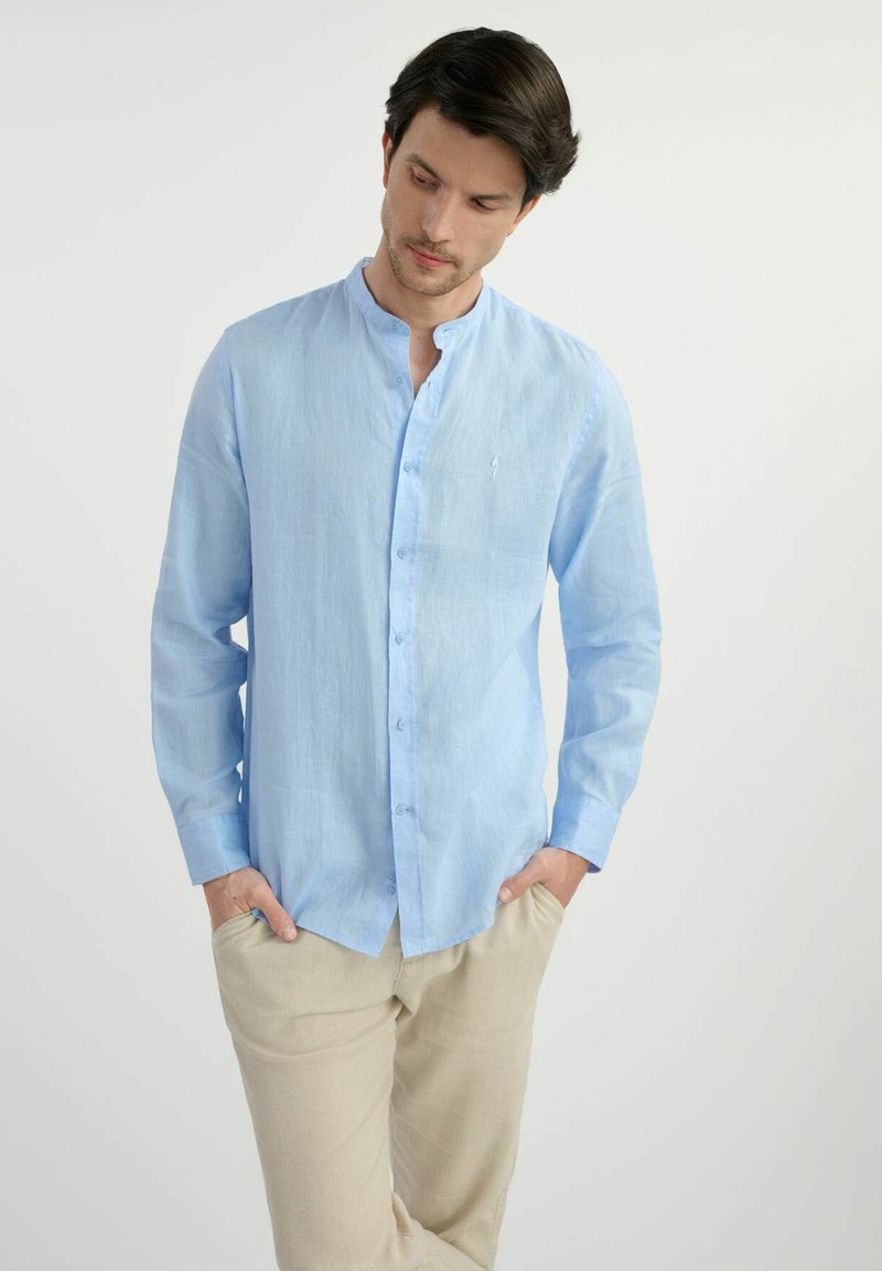 Jasnoniebieska koszula z długim rękawem zapinana na guziki z kołnierzykiem mandaryńskim. Wykonana z lekkiego materiału, charakteryzująca się subtelną teksturą. Minimalistyczny design.