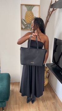 Fekete bőr bevásárlótáska dupla fogantyúval, téglalap alakú, sima felületű, alján diszkrét logóval.